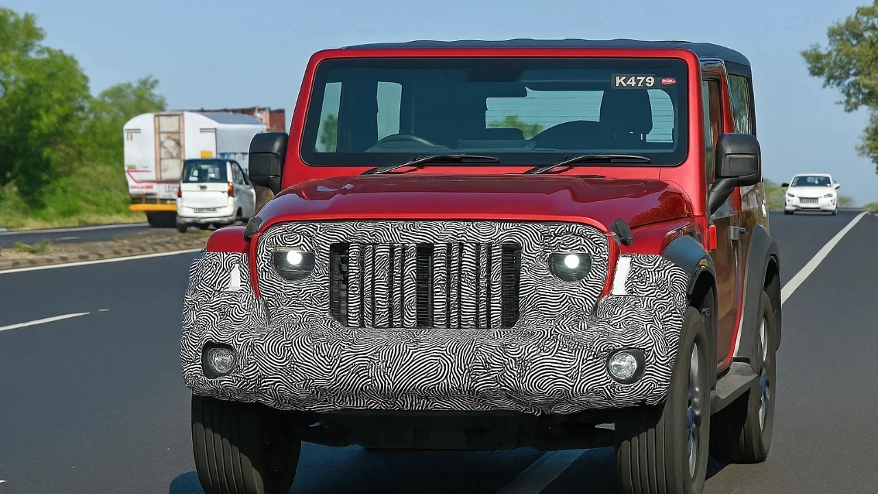 Red Mahindra Thar 3-door facelift prototype with camouflage on the front grille and bumper, spotted during road testing.