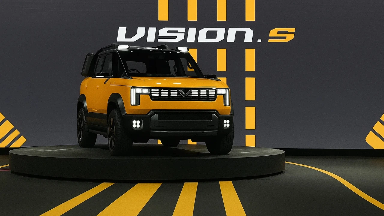 A front view of the yellow Mahindra Vision S concept SUV on a display stage, highlighting its rugged design and LED lights.