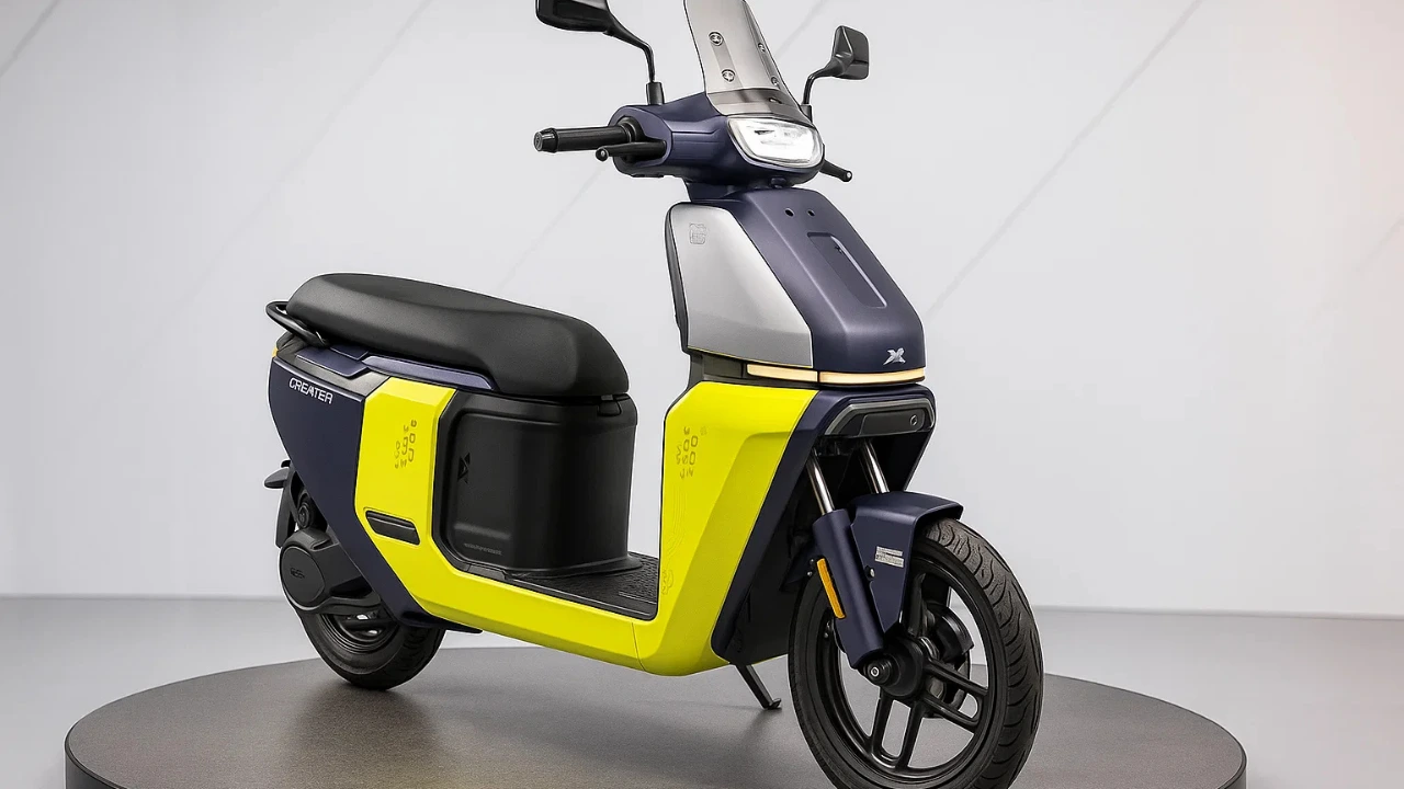 TVS Orbiter electric scooter in dual-tone blue and bright yellow, showcasing its modern, boxy design, flat footboard, and tall windscreen on a display platform.